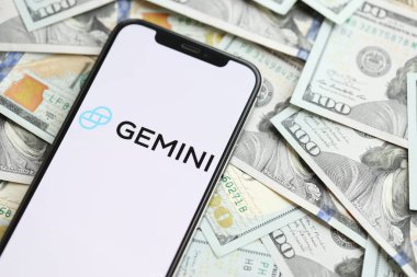 KYIV, UKRAINE - 15 Mart 2024 Gemini logosu iPhone ekranında yüzlerce dolarlık banknotlarla. Kripto döviz portalı