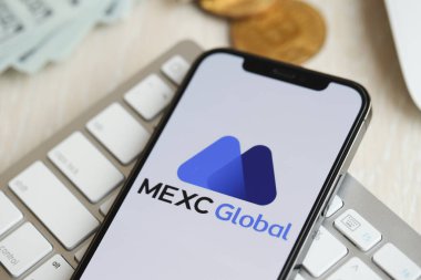 KYIV, UKRAINE - 15 Mart 2024 MEXC logosu iPhone ekranında beyaz klavyede para ve bitcoin ile. Kripto döviz portalı