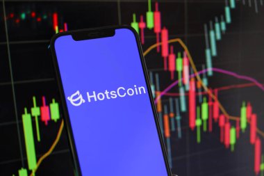 KYIV, UKRAINE - MARCH 15, 2024 Hotscoin logo on iPhone display screen and crypto currency value charts. Cryptocurrency exchange portal clipart