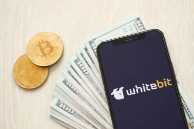 KYIV, UKRAINE - 15 Mart 2024 Whitebit logosu iPhone ekranında dolar ve bitcoin ile. Kripto döviz portalı