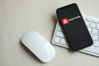 KYIV, UKRAINE - 17 Mart 2024 Adobe Firefly logosu iPhone ekranında elma klavyesi ve fareyle birlikte. Yapay Zeka Motoru