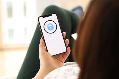 KYIV, UKRAINE - 1 Nisan 2024 OnlyFans simgesi kapalı alandaki genç kadınların elinde akıllı telefon ekranında. iPhone uygulaması kullanan kadın