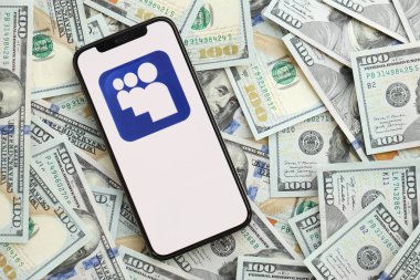 KYIV, UKRAINE - 1 Nisan 2024 Myspace simgesi akıllı telefon ekranında ve birçok kullanım dışı para banknotları. Uygulama logolu iPhone görüntüsü ve bir sürü yüz dolarlık banknotlar