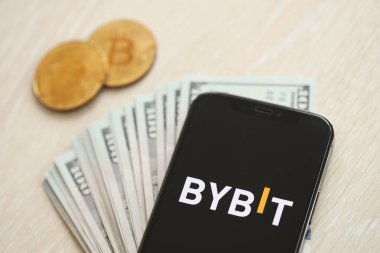 KYIV, UKRAINE - 15 Mart 2024 Bybit logosu iPhone ekranında dolar ve bitcoin ile birlikte. Kripto döviz portalı