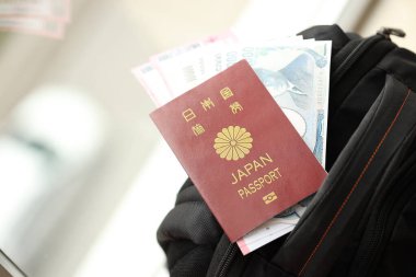 Japon yenli Japonya pasaportu. Sırt çantasında uçak biletleri olan para faturaları.