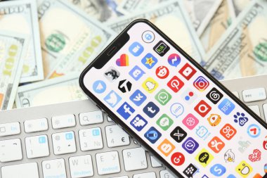KYIV, UKRAINE - Nisan 1, 2024 Birçok akıllı telefon ekranındaki birçok uygulama simgesi. Uygulama logosuna sahip iPhone görüntüsü ve beyaz klavyeli dolar banknotları