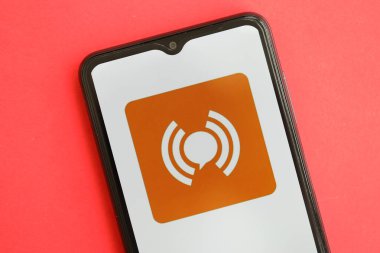 KYIV, UKRAINE - 1 Nisan 2024 WeiTao simgesi kırmızı masadaki akıllı telefon ekranında. Parlak kırmızı arkaplanda uygulama logosuna sahip iPhone görüntüsü