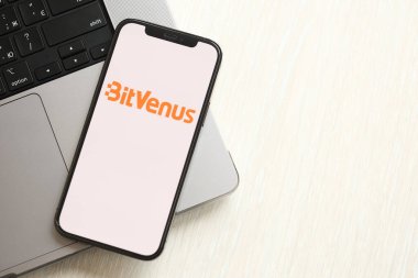 KYIV, UKRAINE - 15 Mart 2024 Bitvenus logosu MacBook panelinde iPhone ekranında. iPhone ekranındaki şifreli döviz portalı logosu ve MacBook 'ta dolar ve bitcoin' ler.