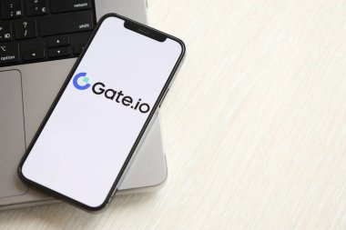 KYIV, UKRAINE - 15 Mart 2024 Gate.io logosu iPhone ekranında MacBook panelinde. iPhone ekranında şifreli döviz portalı logosu ve MacBook 'ta dolar ve bitcoin var. Kripto para birimi