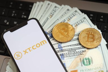 KYIV, UKRAINE - 15 Mart 2024 XTcom logosu iPhone ekranında dolar ve bitcoin ile MacBook üzerinde. Kripto döviz portalı