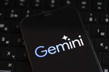 KYIV, UKRAINE - iPhone ekranında 17 Mart 2024 Gemini logosu ve MacBook klavyesi. Yapay Zeka Motoru