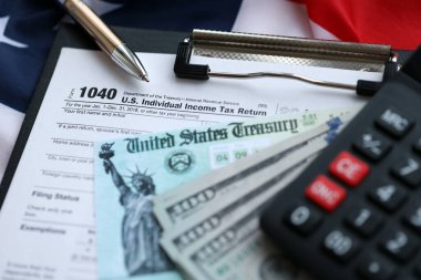 United States 1040 tax form individual income tax return with refund check and US dollar bills close up clipart