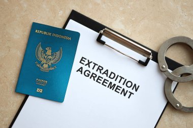 Passport of Indonesia and Extradition Agreement with handcuffs on table close up clipart
