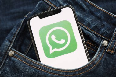 KYIV, UKRAINE - APRIL 1, 2024 Whatsapp messenger icon on smartphone display screen in jeans pocket. iPhone display with app logo hide in fashionable denims pocket close up clipart