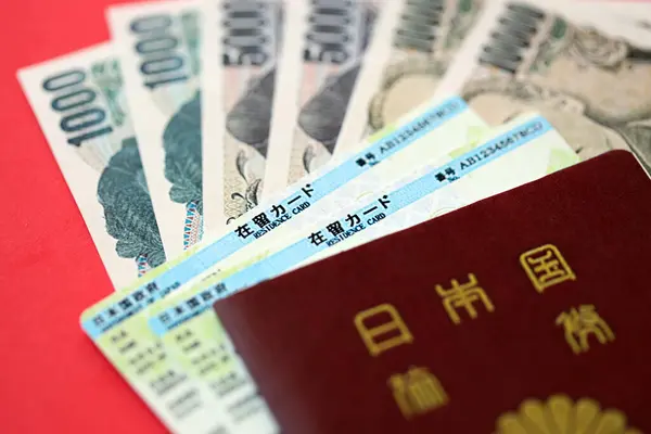 stock image Green residence card of Japan with passport and japanese yen money on red background close up