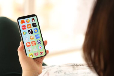 KYIV, UKRAINE - Nisan 1, 2024 Asya uygulamaları simgesi akıllı telefon ekranında kapalı alanda genç kadınların elinde. iPhone uygulaması kullanan kadın