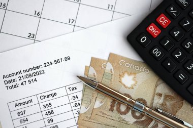 Hesaplamaların çoğu, Kanada 'nın para, hesap makinesi ve kaleminin yakın plan yapılmasıyla sonuçlanır. Kanada 'da vergilendirme ve yıllık muhasebeci evrakları