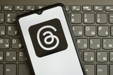 KYIV, UKRAINE - Nisan 1, 2024 Siyah klavyede akıllı telefon ekranındaki iplik simgesi. Koyu tuş takımı düğmelerinde uygulama logosu olan iPhone görüntüsü