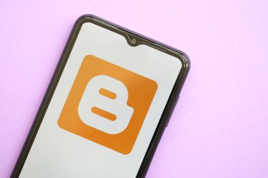 KYIV, UKRAINE - 1 Nisan 2024 Blogger simgesi mor masadaki akıllı telefon ekranında. Leylak arka planında uygulama logosu olan iPhone görüntüsü