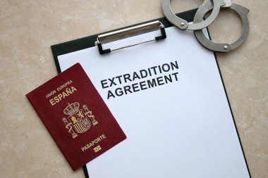 Passport of Spain and Extradition Agreement with handcuffs on table close up clipart