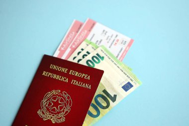 Paralı İtalyan pasaportu ve mavi arka planda uçak biletleri. Turizm ve seyahat kavramı