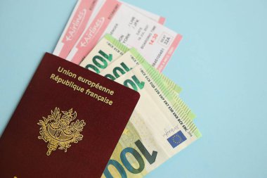 Fransız pasaportu ve avroluk parayla mavi arka planda uçak biletleri. Turizm ve seyahat kavramı