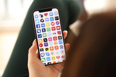 KYIV, UKRAINE - Nisan 1, 2024 Birçok uygulama simgesi akıllı telefon ekranında kapalı alanda genç kadınların elinde. iPhone uygulaması kullanan kadın