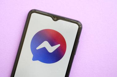 KYIV, UKRAINE - 1 Nisan 2024 Facebook Messenger simgesi mor masadaki akıllı telefon ekranında. Leylak arka planında uygulama logosu olan iPhone görüntüsü