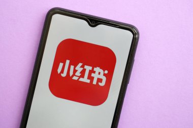 KYIV, UKRAINE - 1 Nisan 2024 Xiaohongshu simgesi mor masadaki akıllı telefon ekranında. Leylak arka planında uygulama logosu olan iPhone görüntüsü