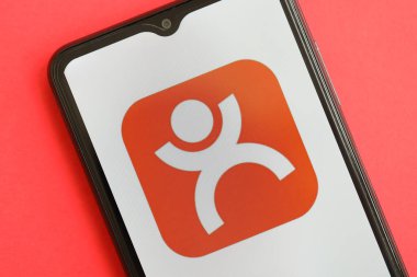 KYIV, UKRAINE - 1 Nisan 2024 Kırmızı masadaki akıllı telefon ekranında dianping platform simgesi. Parlak kırmızı arkaplanda uygulama logosuna sahip iPhone görüntüsü