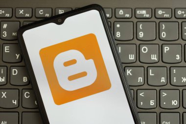 KYIV, UKRAINE - Nisan 1, 2024 Blogger simgesi siyah klavyede akıllı telefon ekranında. Koyu tuş takımı düğmelerinde uygulama logosu olan iPhone görüntüsü