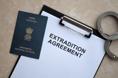 Passport of India and Extradition Agreement with handcuffs on table close up clipart