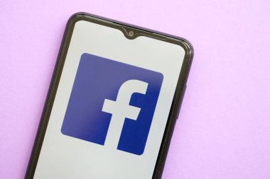 KYIV, UKRAINE - 1 Nisan 2024 Facebook simgesi mor masadaki akıllı telefon ekranında. Leylak arka planında uygulama logosu olan iPhone görüntüsü