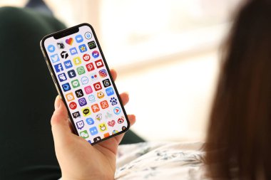 KYIV, UKRAINE - Nisan 1, 2024 Birçok uygulama simgesi akıllı telefon ekranında kapalı alanda genç kadınların elinde. iPhone uygulaması kullanan kadın