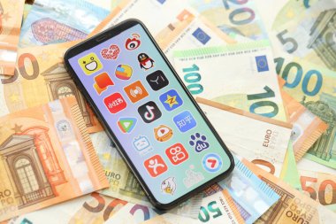 KYIV, UKRAINE - 1 Nisan 2024 Asya uygulama simgesi birçok avro para banknotlarında akıllı telefon ekranında. Avrupa para birimi euro banknotlu uygulama logosuyla iPhone görüntüsü