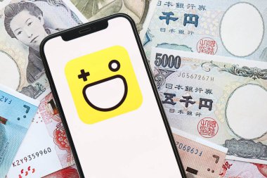 KYIV, UKRAINE - 1 Nisan 2024 Hago simgesi birçok Asya para bankasında akıllı telefon ekranında. Japon yen ve Çin Yuan banknotları içeren uygulamalı iPhone ekranı