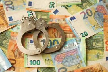Many European euro money bills and handcuffs. Lot of banknotes of European union currency and cuffs close up clipart