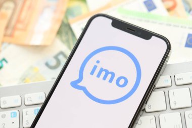KYIV, UKRAINE - 1 Nisan 2024 İmo kurye simgesi birçok avro para bankasında akıllı telefon ekranında. Avrupa para birimi avro banknotları ve beyaz klavyeli uygulamalı iPhone görüntüsü