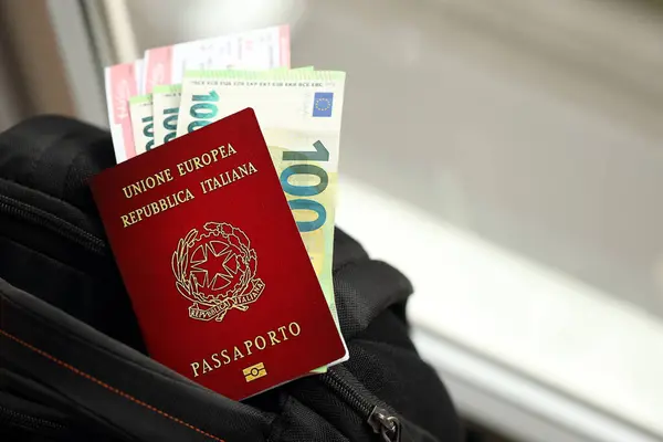 Italian passport and euro money bills with airline tickets on backpack close up