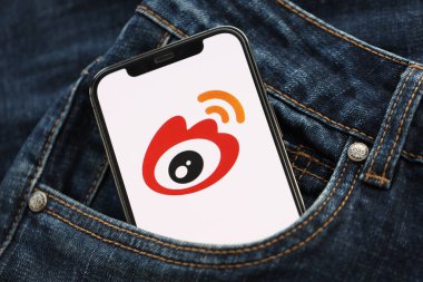 KYIV, UKRAINE - 1 Nisan 2024 Sina Weibo simgesi kot pantolon cebinde akıllı telefon ekranında. Uygulama logosuna sahip iPhone görüntüsü. Moda görünümlü kotların cebinde gizleniyor.