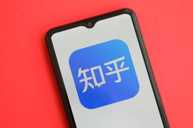 KYIV, UKRAINE - 1 Nisan 2024 Zhihu simgesi kırmızı masadaki akıllı telefon ekranında. Parlak kırmızı arkaplanda uygulama logosuna sahip iPhone görüntüsü