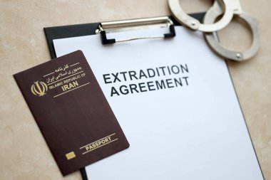 Passport of Iran and Extradition Agreement with handcuffs on table close up clipart