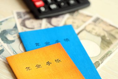 Japon emeklilik sigortası broşürleri yeni para faturaları ve hesap makineleri ile masaya yakın.