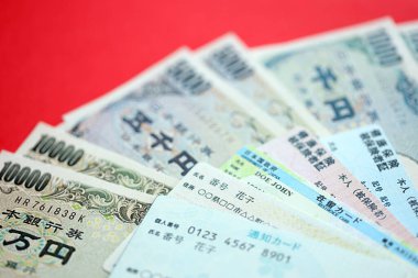 Açık mavi ve kırmızı Japon Sağlık Sigortası kartları Japon ikamet kartı ve telefon kartımla birlikte masada.