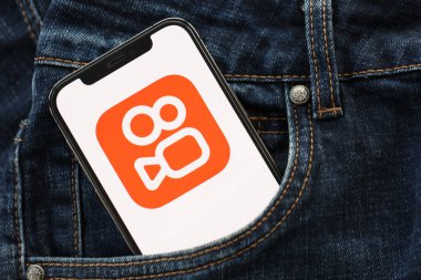KYIV, UKRAINE - 1 Nisan 2024 Kuaishou platform simgesi kot pantolon cebinde akıllı telefon ekranında. Uygulama logosuna sahip iPhone görüntüsü. Moda görünümlü kotların cebinde gizleniyor.