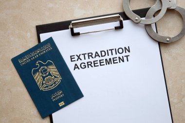 Passport of United Arab Emirates and Extradition Agreement with handcuffs on table close up clipart