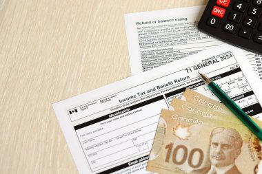Kanada T1 Genel vergi formu gelir vergisi ve kar iadesi Kanada 'nın para faturalarıyla birlikte masada yatıyor. Kanada 'da vergilendirme ve yıllık muhasebeci evrakları