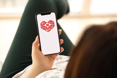 KYIV, UKRAINE - Nisan 1, 2024 Pinduoduo simgesi akıllı telefon ekranında kapalı alanda genç kadınların elinde. iPhone uygulaması kullanan kadın