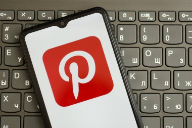 KYIV, UKRAINE - Nisan 1, 2024 Pinterest simgesi siyah klavyede akıllı telefon ekranında. Koyu tuş takımı düğmelerinde uygulama logosu olan iPhone görüntüsü
