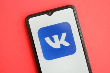 KYIV, UKRAINE - 1 Nisan 2024 Vkontakte simgesi kırmızı masadaki akıllı telefon ekranında. Parlak kırmızı arkaplanda uygulama logosuna sahip iPhone görüntüsü